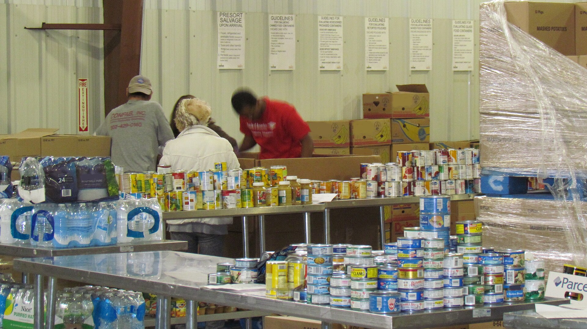 Volunteers sorting donated food onto tables at a community food bank.